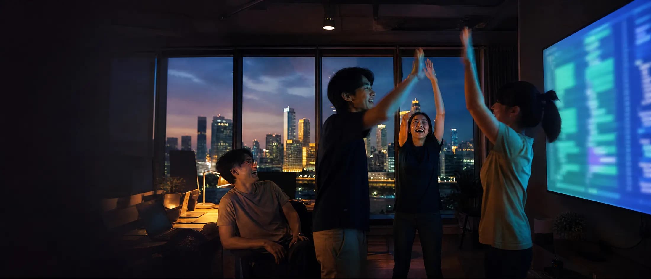 ทีมพัฒนาฉลองหลัง deploy สำเร็จในออฟฟิศยามค่ำ